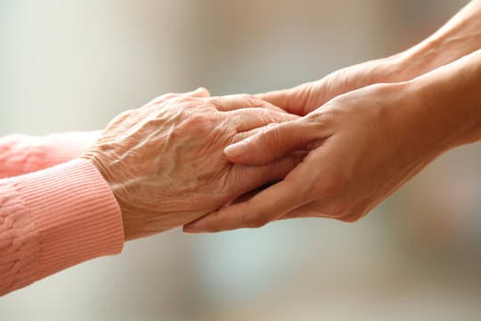 Caring hands holding an elderly person's hands